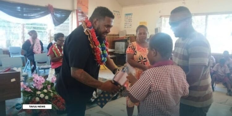MID Minister Fuo’o presenting a gift to one of the students accompanied by his father.