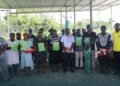 Member of Parliament for NGC, Dr. Paul Bosawai, with school recipient representatives flanked by constituency officers, showing off their handover certificates and some of the handover material supplies.