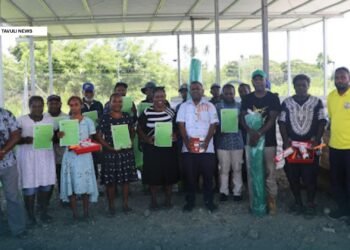Member of Parliament for NGC, Dr. Paul Bosawai, with school recipient representatives flanked by constituency officers, showing off their handover certificates and some of the handover material supplies.